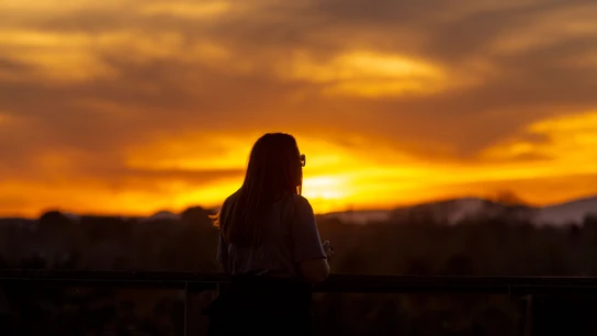 Una mujer observa la puesta de sol en una imagen de archivo Una mujer observa la puesta de sol en una imagen de archivo
