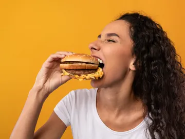 Una mujer comiéndose una hamburguesa Una mujer comiéndose una hamburguesa