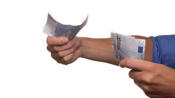 Las manos de un hombre sosteniendo varios billetes de 20 euros