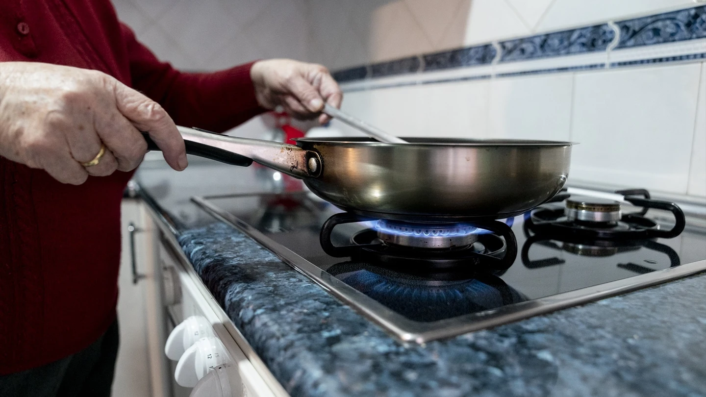 Una persona cocina sobre un fuego de cocina de gas Una persona cocina sobre un fuego de cocina de gas