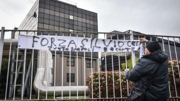 Un seguidor de Silvio Berlusconi cuelga una pancarta de "Fuerza Silvio" a las puertas del hospital en el que se encuentra ingresado.