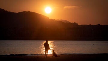 Una joven observa el amanecer en la playa de Ondarreta de San Sebastián.