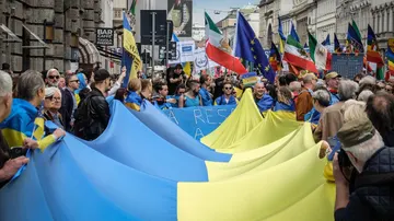 La gente sostiene la bandera de Ucrania durante una manifestación para conmemorar el 78 aniversario del Día de la Liberación, en Milán.