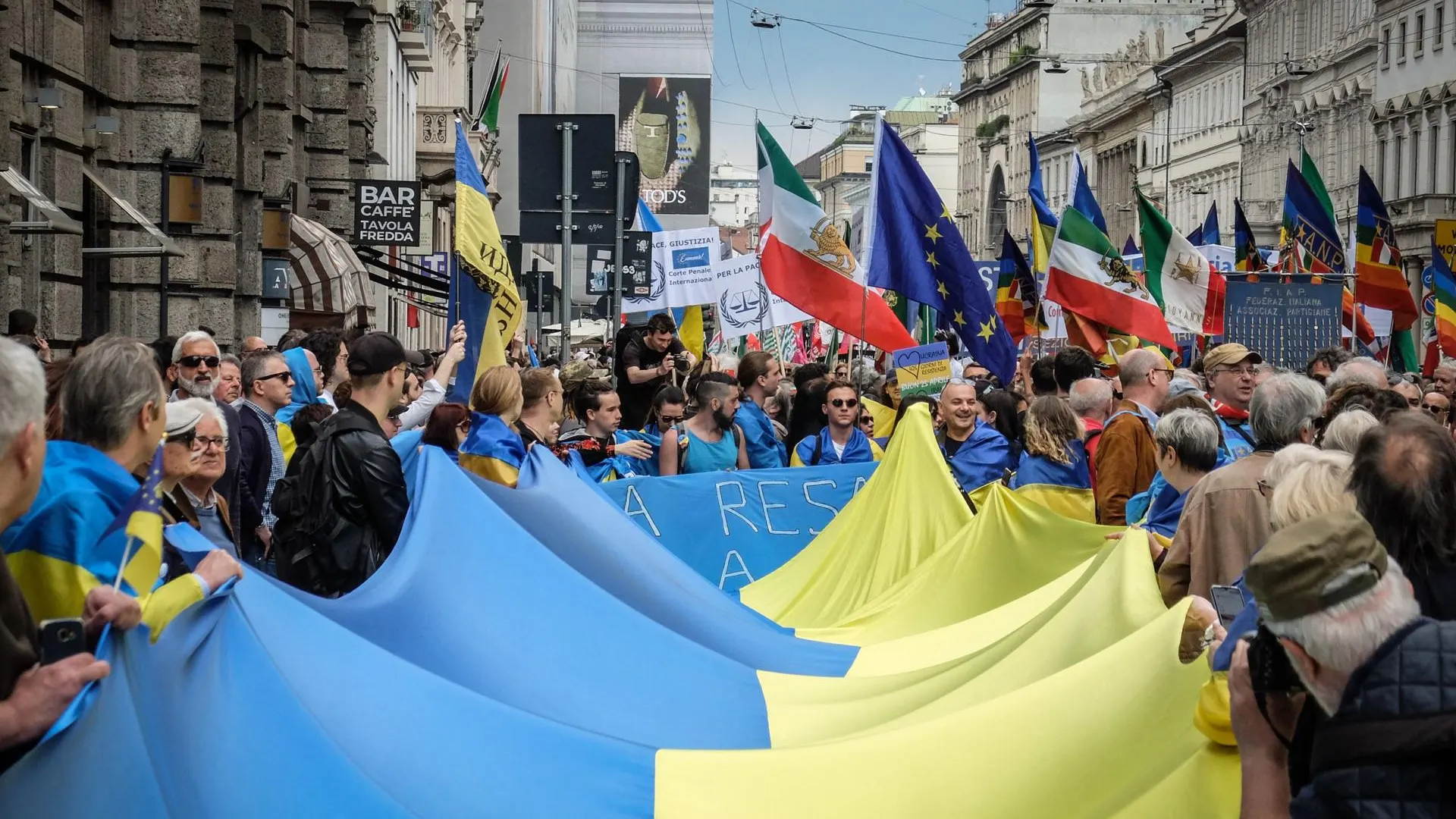 La gente sostiene la bandera de Ucrania durante una manifestación para conmemorar el 78 aniversario del Día de la Liberación, en Milán.