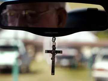Cruz colgada en el espejo retrovisor central de un coche Cruz colgada en el espejo retrovisor central de un coche