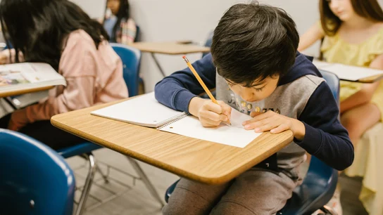 Un alumno escribe en un aula de un colegio Un alumno escribe en un aula de un colegio