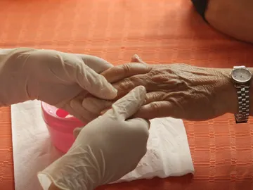 Una mano de una persona anciana sostenida por una cuidadora Una mano de una persona anciana sostenida por una cuidadora