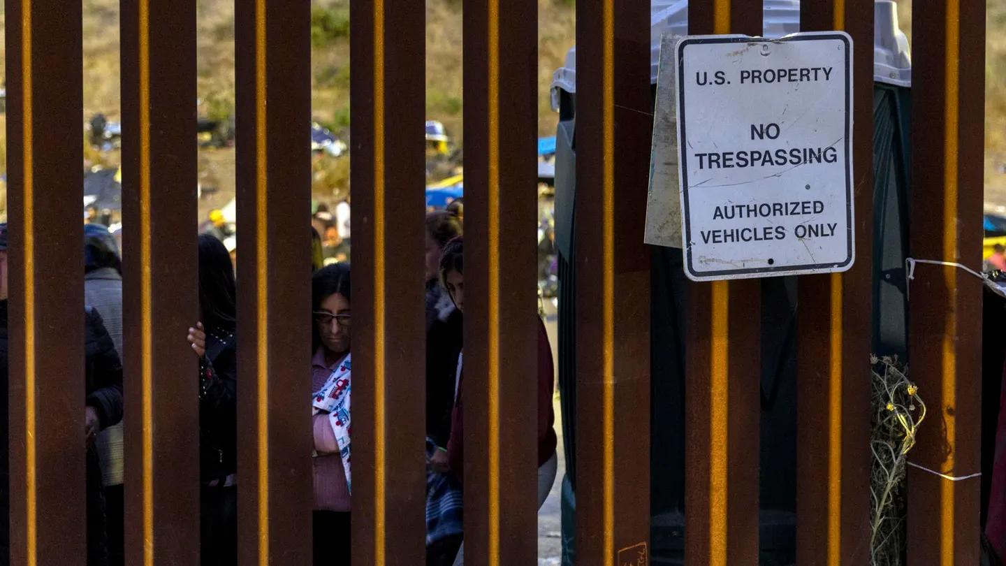 Migrantes miran a través del muro entre Estados Unidos y México, en San Diego, California, 12 de mayo de 2023. Migrantes miran a través del muro entre Estados Unidos y México, en San Diego, California, 12 de mayo de 2023.