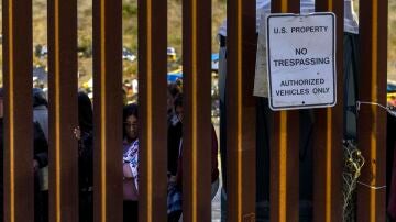Migrantes miran a través del muro entre Estados Unidos y México, en San Diego, California, 12 de mayo de 2023.