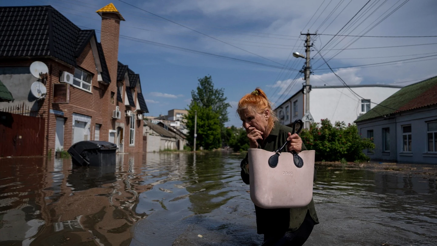 Una mujer camina en un pueblo anegado tras el derrumbe de la presa Nova Kajovka Una mujer camina en un pueblo anegado tras el derrumbe de la presa Nova Kajovka
