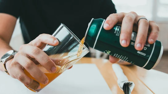 Un hombre sirviéndose una lata de cerveza fresquita en un vaso Un hombre sirviéndose una lata de cerveza fresquita en un vaso