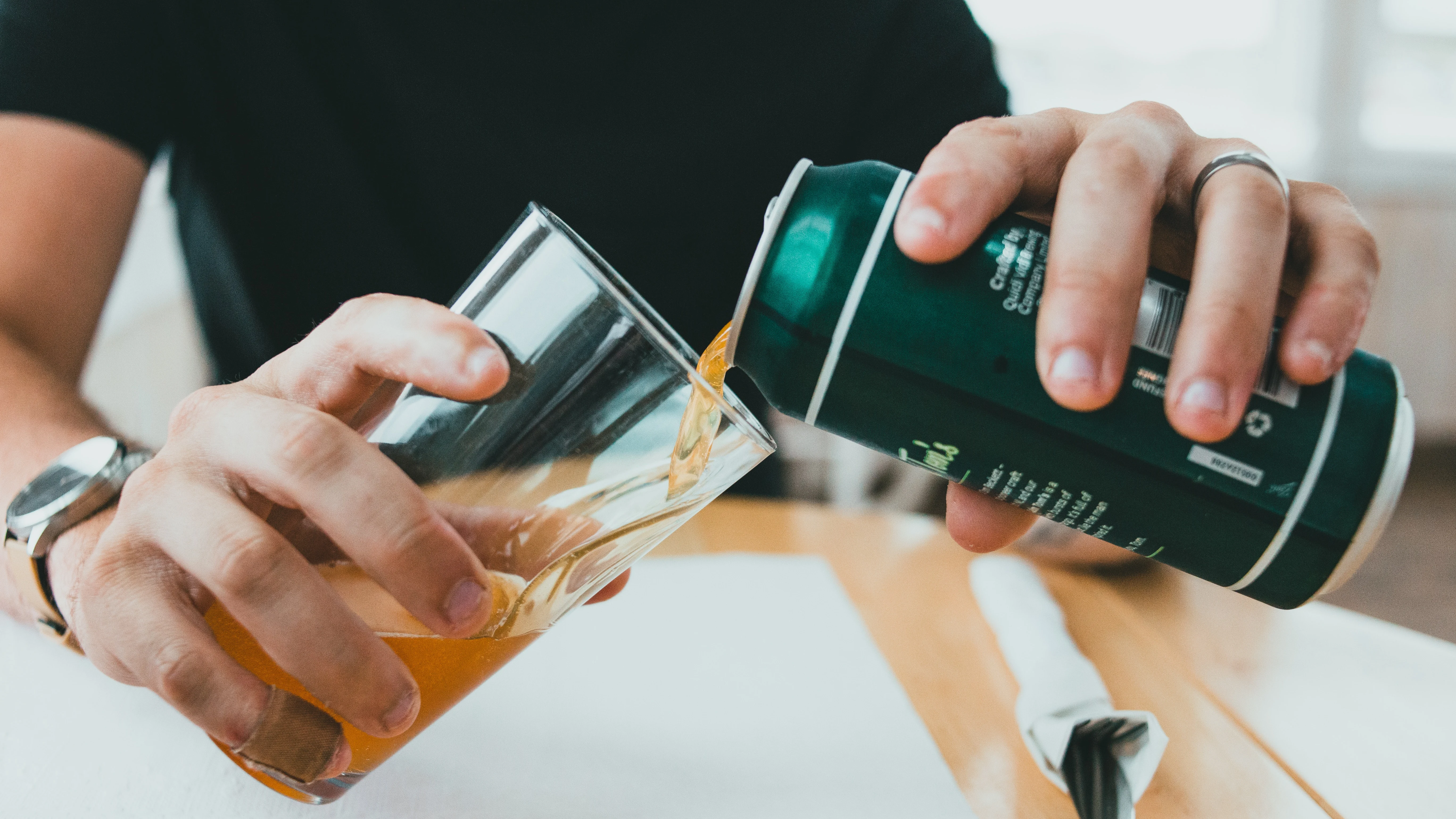 Un hombre sirviéndose una lata de cerveza fresquita en un vaso