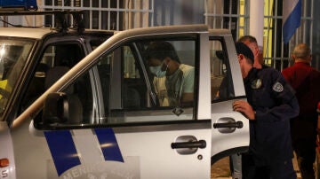 Oficial de policía portuaria escolta a un hombre egipcio, parte de un grupo de nueve egipcios que fueron arrestados por el naufragio.