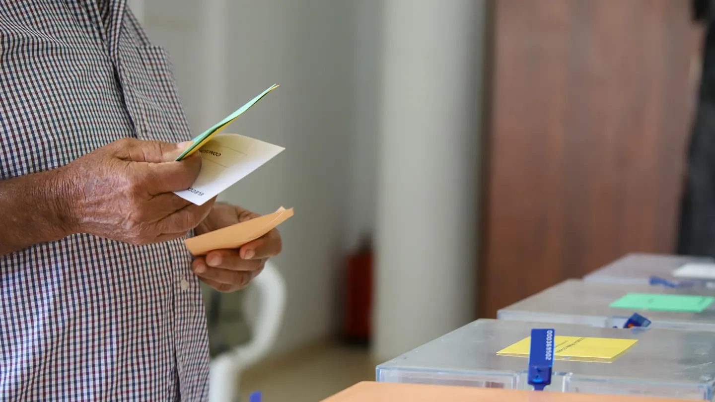 Un hombre sostiene sus papeletas de votación ante las urnas de la mesa en el colegio electoral. Un hombre sostiene sus papeletas de votación ante las urnas de la mesa en el colegio electoral.