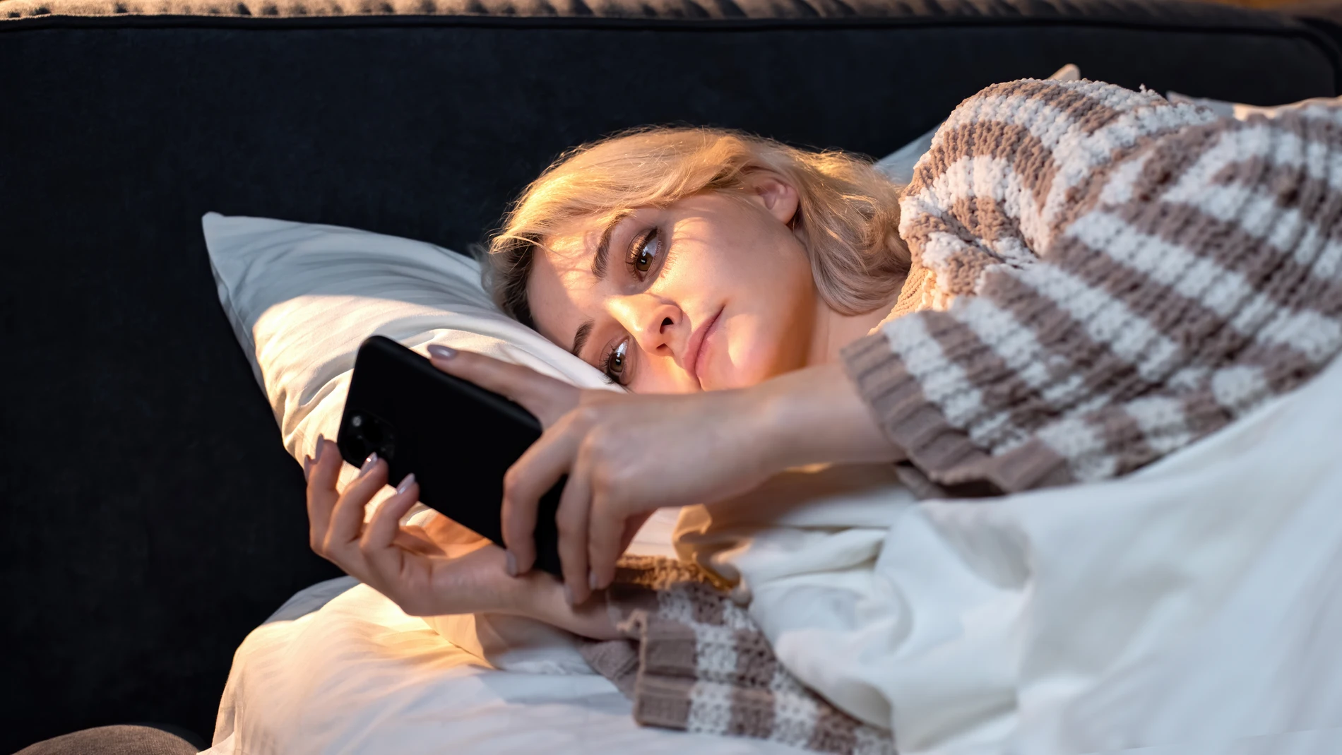 Un mujer mirando el móvil antes de dormir.