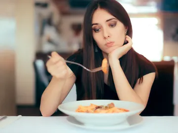 Mujer triste mirando un plato de comida Mujer triste mirando un plato de comida