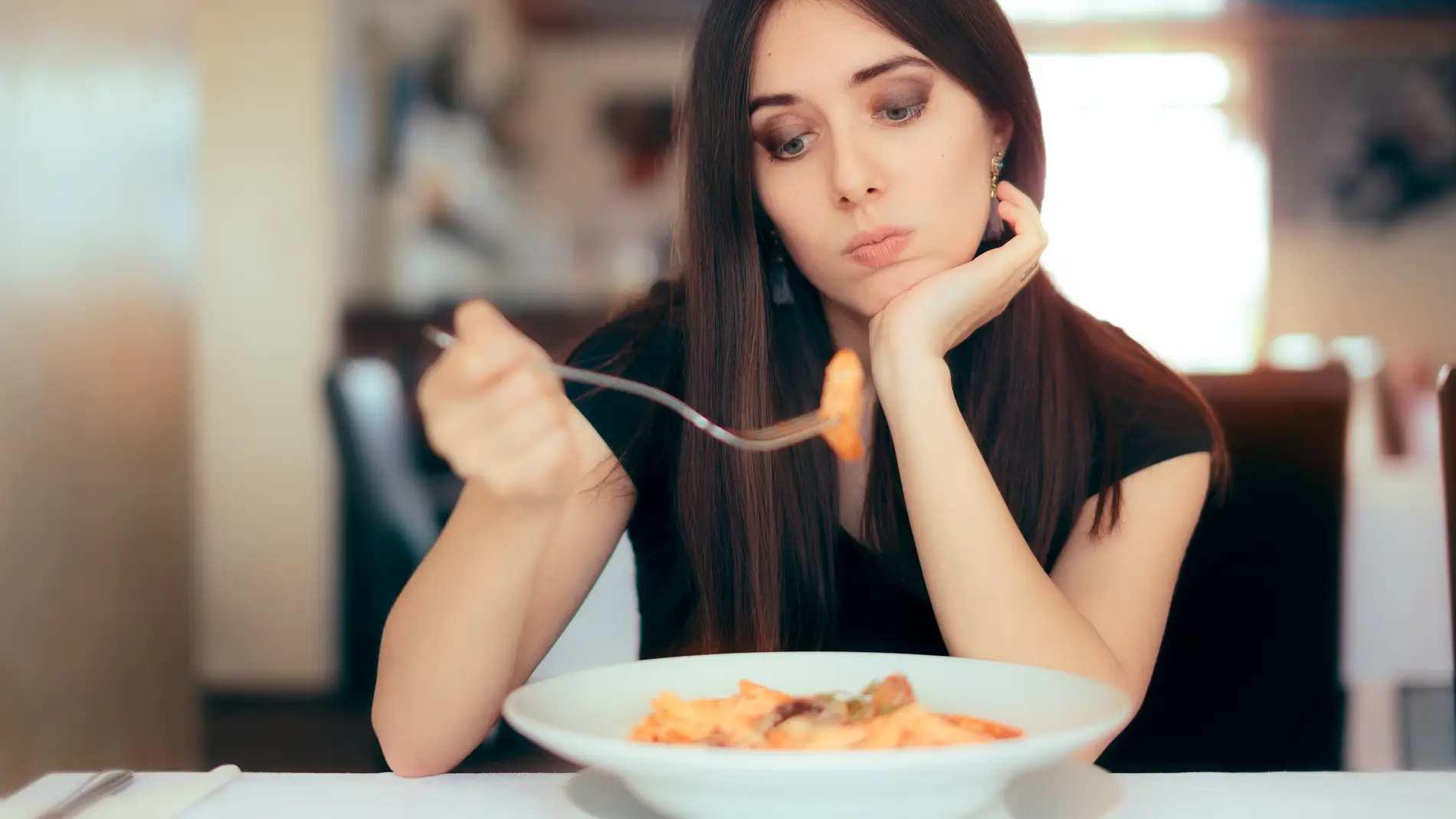 Mujer triste mirando un plato de comida