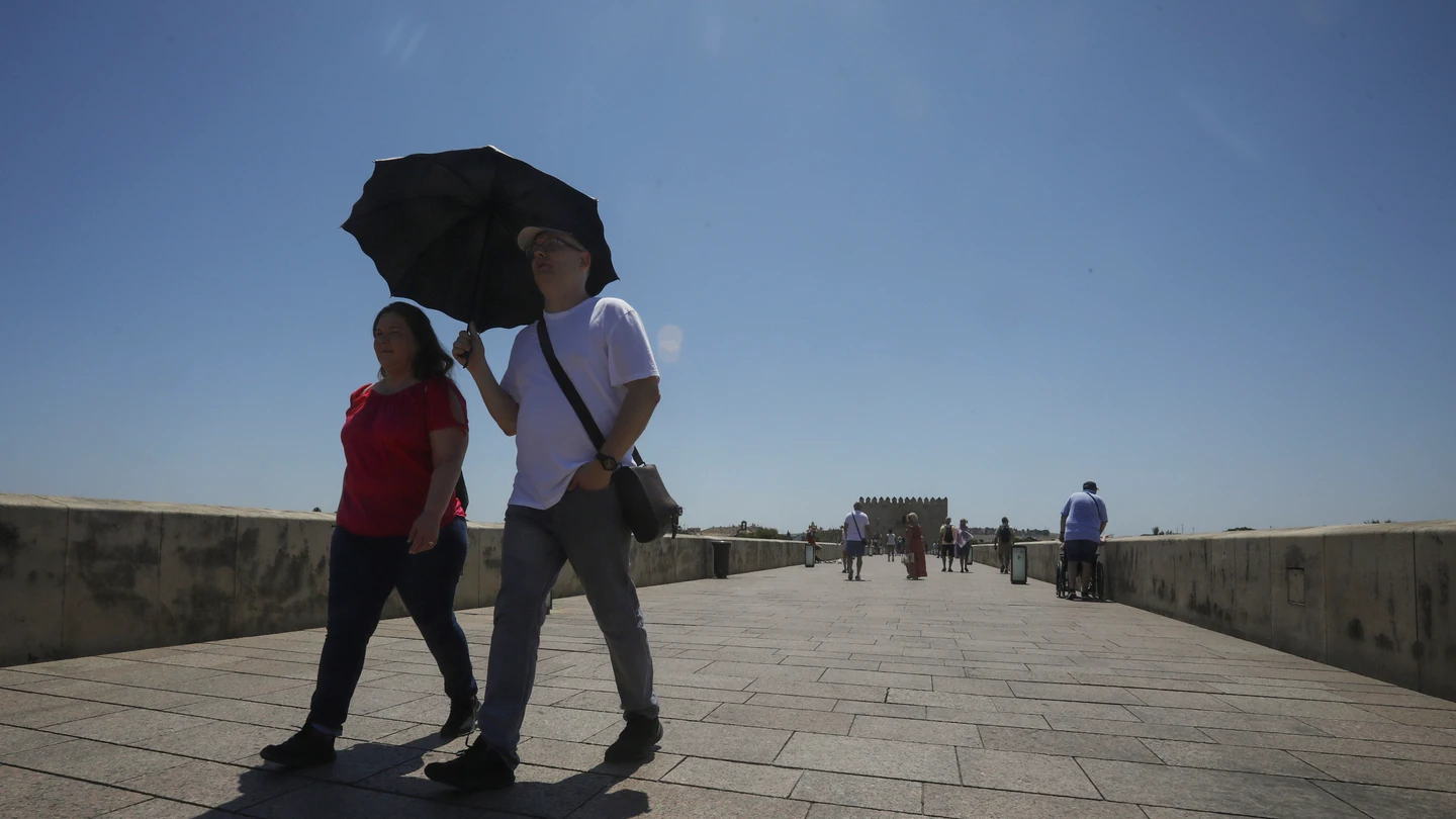 Imagen de archivo de turistas paseando por el Puente Romano de Córdoba protegiéndose frente al calor Imagen de archivo de turistas paseando por el Puente Romano de Córdoba protegiéndose frente al calor