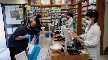 Dos personas son atendidas en una farmacia de Madrid.
