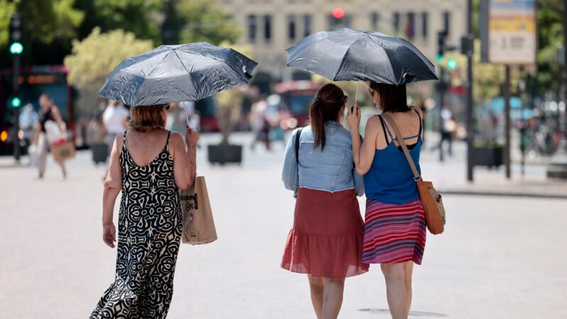 Tres mujeres se protegen del calor con unos paraguas