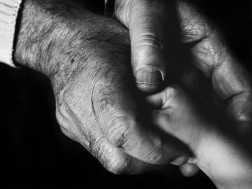 Un anciano sostiene la mano de una niña