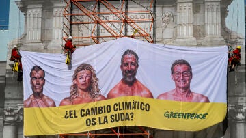 Greenpeace cuelga una lona en la Puerta de Alcalá con la cara de los candidatos: "¿El cambio climático os la suda?"