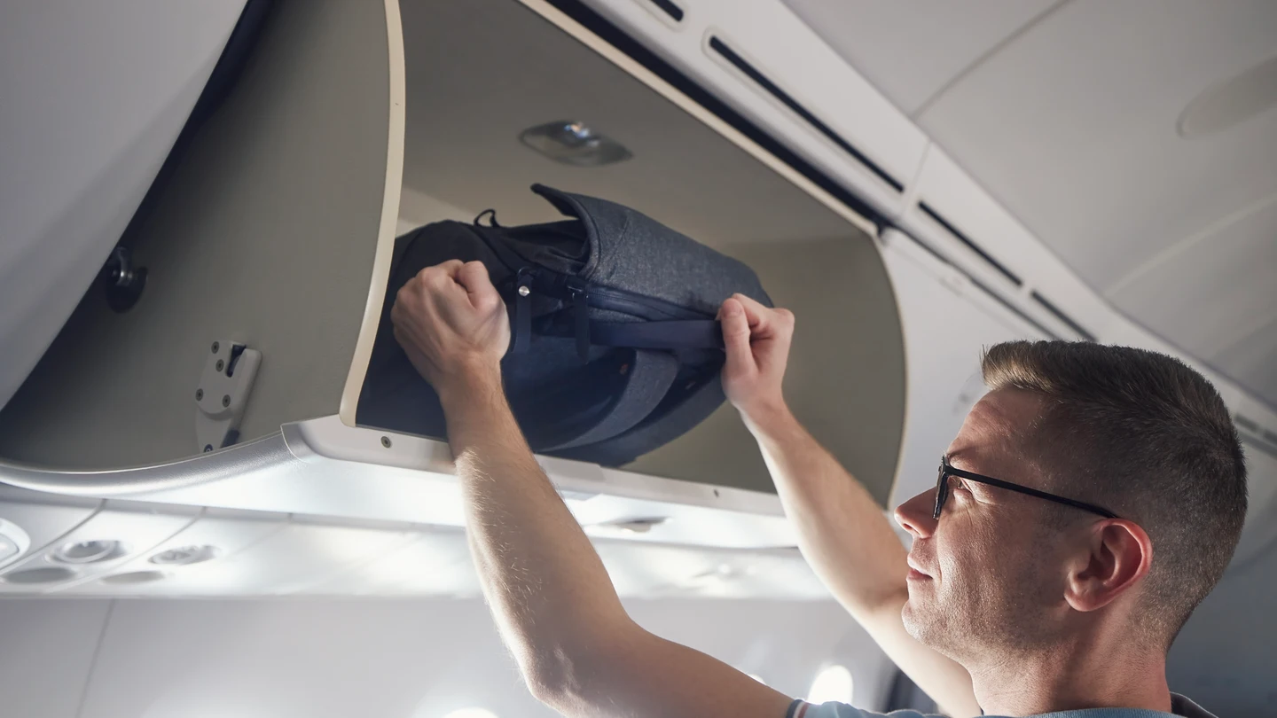 Hombre viajando con una mochila en el avión Hombre viajando con una mochila en el avión