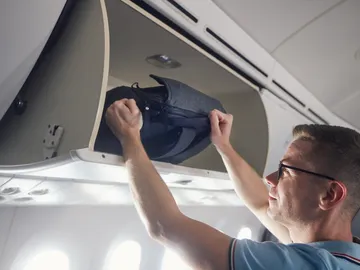 Hombre viajando con una mochila en el avión Hombre viajando con una mochila en el avión
