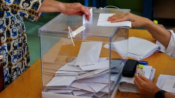 Una mujer introduce su voto en una urna en un colegio electoral del centro de Sevilla. 