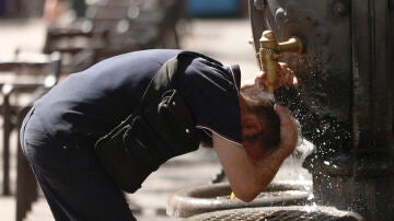 Un hombre se refresca en una fuente en el centro de Barcelona, este martes, cuando las temperaturas ya están escalando con intensidad en Cataluña.
