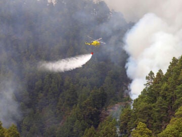 Un helicóptero vierte agua sobre el bosque incendiado en La Palma