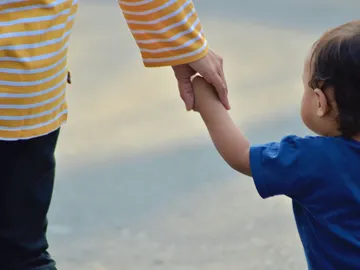 Un niño pequeño y otro más mayor se dan la mano Un niño pequeño y otro más mayor se dan la mano