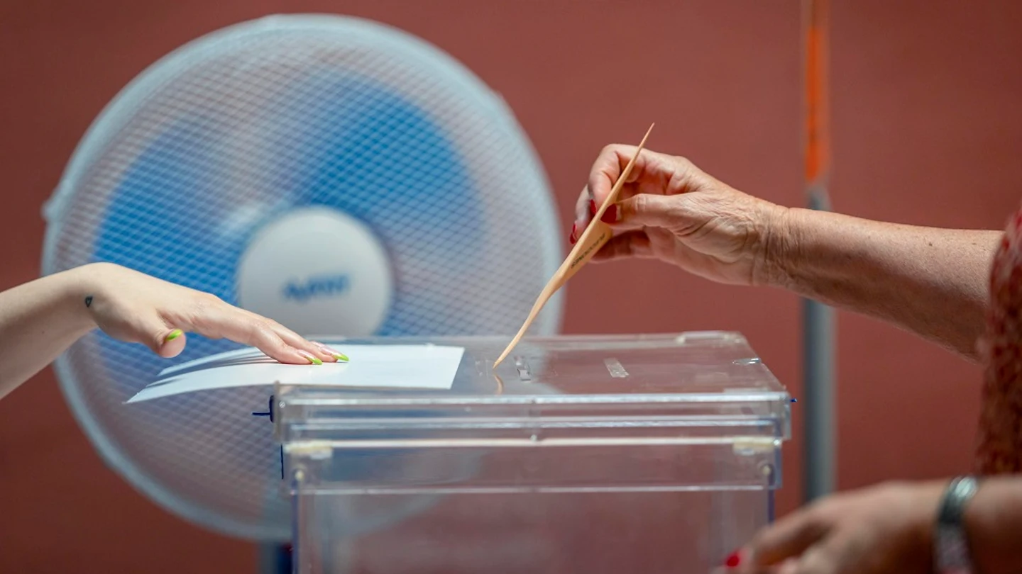 Una persona depositando su voto en una urna Una persona depositando su voto en una urna