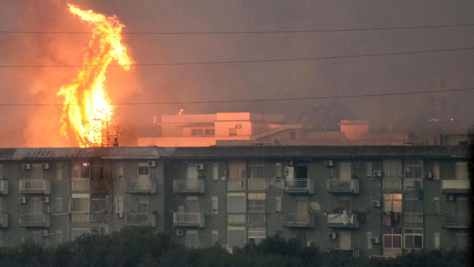 Una columna de fuego se eleva tras un bloque de viviendas en el área de Monte Grifone en la ciudad de Ciaculli, cerca de Palermo