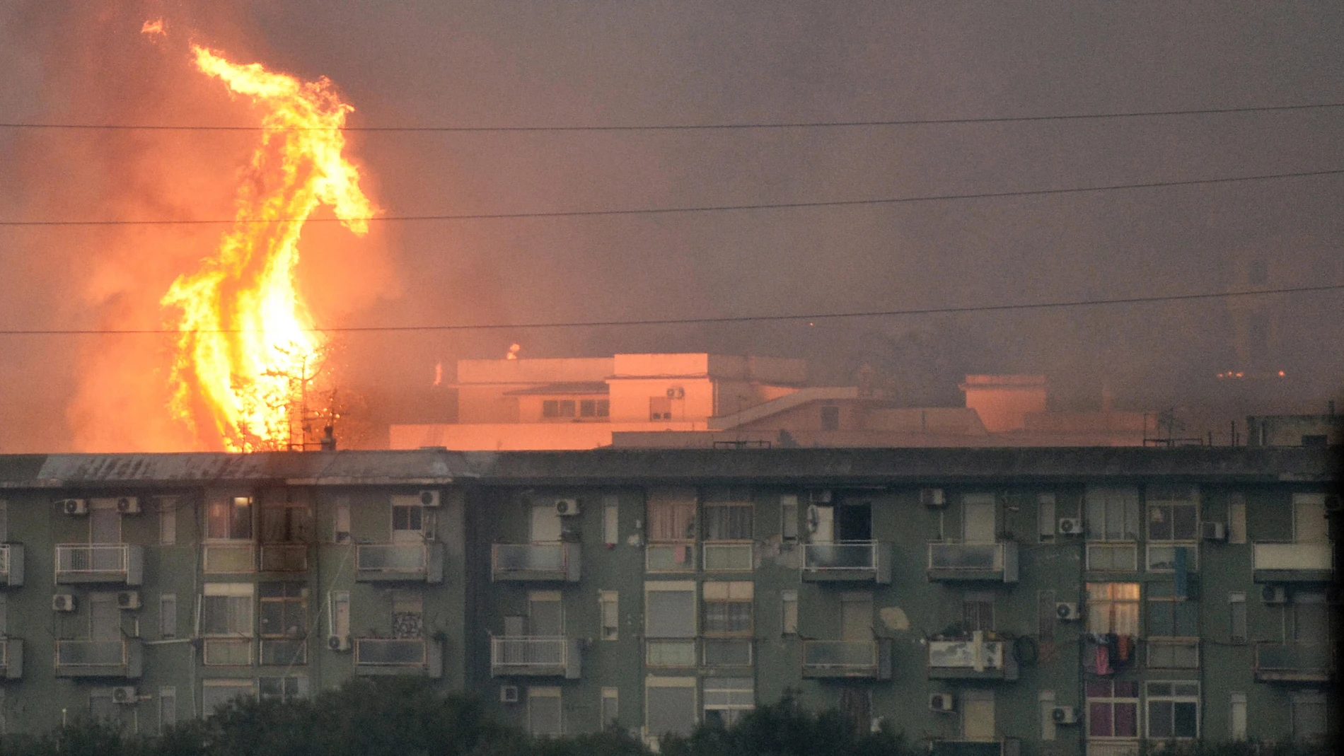 Una columna de fuego se eleva tras un bloque de viviendas en el área de Monte Grifone en la ciudad de Ciaculli, cerca de Palermo, este martes. 