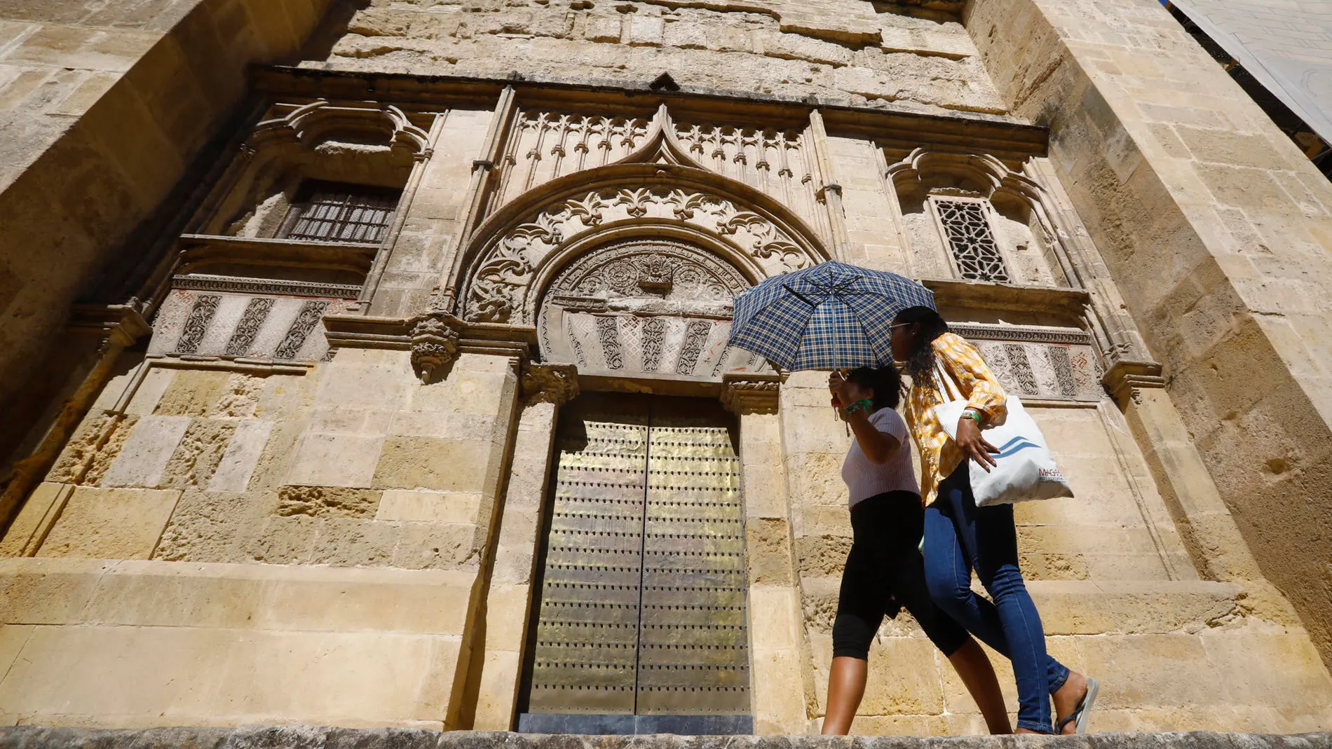 Dos turistas se protegen con un paraguas de las altas temperaturas junto a la mezquita-catedral de Córdoba.