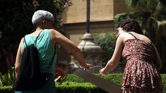 Dos mujeres se refrescan en una fuente Dos mujeres se refrescan en una fuente