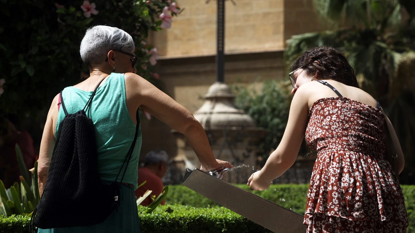Dos mujeres se refrescan en una fuente Dos mujeres se refrescan en una fuente