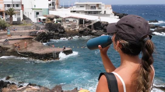 Una mujer bebe agua en una zona de la costa de Güímar en Tenerife, uno de los trece municipios declarados en alerta roja. Una mujer bebe agua en una zona de la costa de Güímar en Tenerife, uno de los trece municipios declarados en alerta roja.
