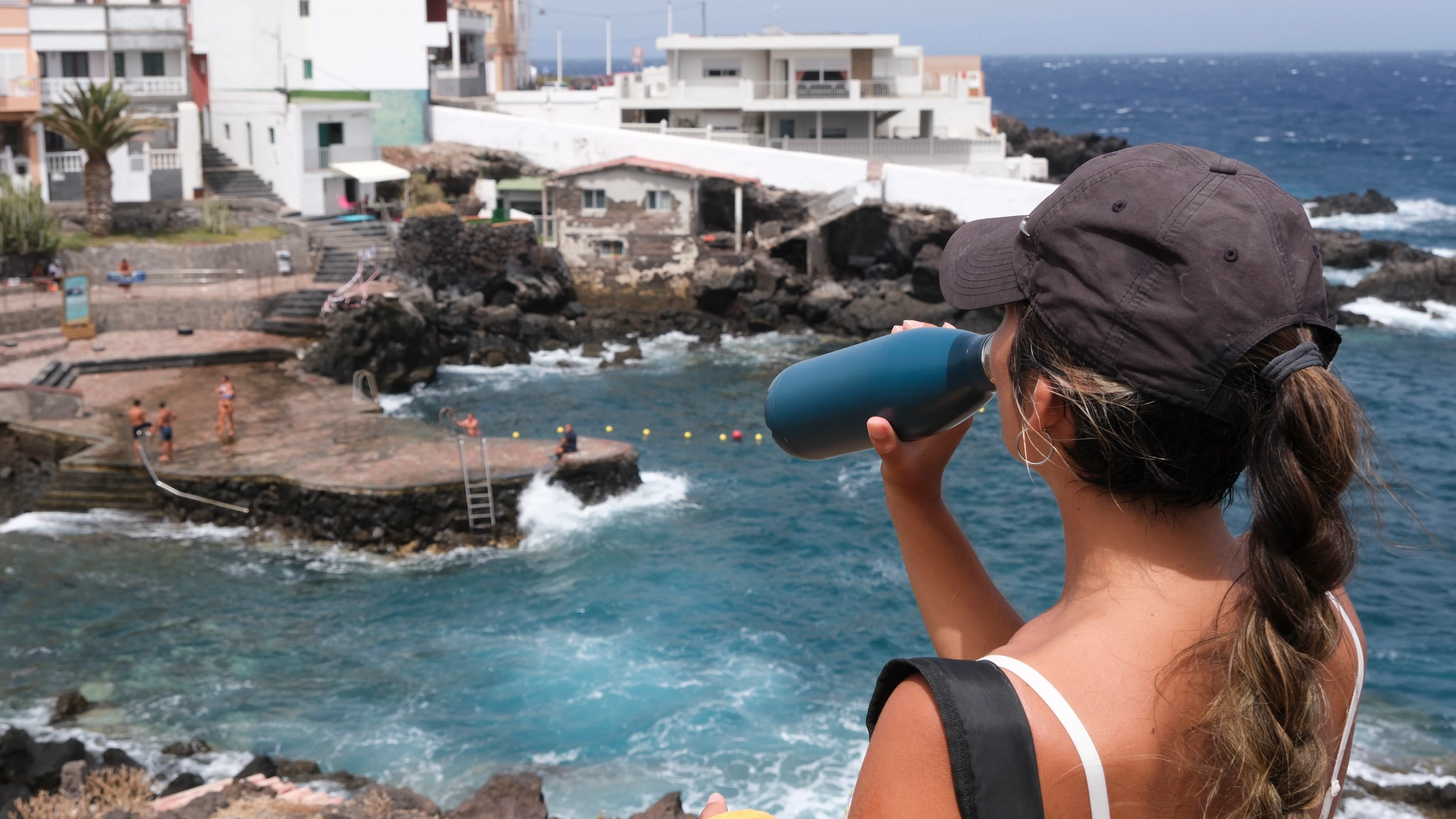 Una mujer bebe agua en una zona de la costa de Güímar en Tenerife, uno de los trece municipios declarados en alerta roja.