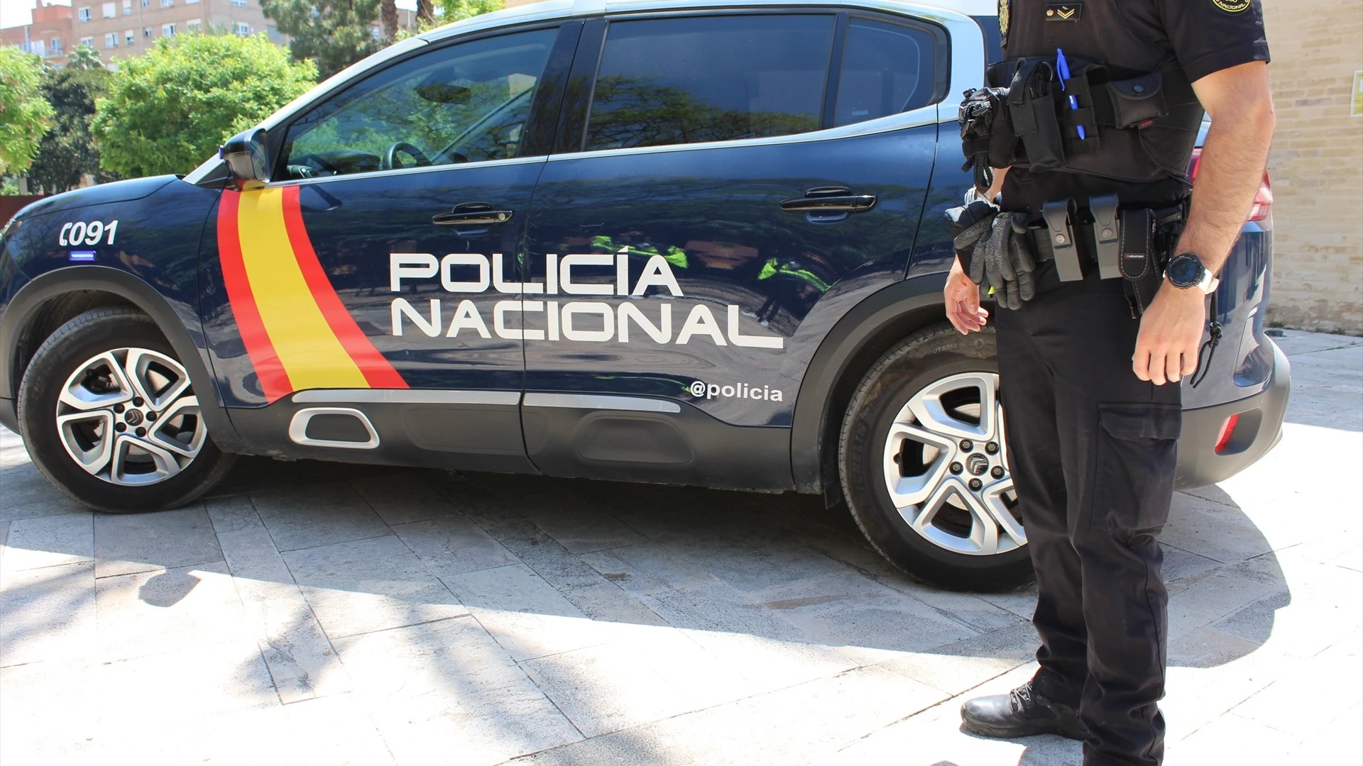 Imagen de archivo de un agente junto a un coche de la Policía Nacional.