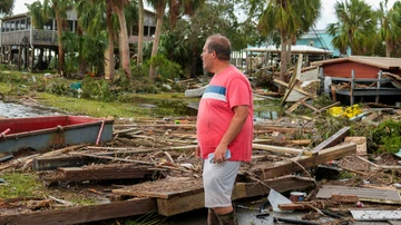 A man contemplates the remains of his business, now completely destroyed.