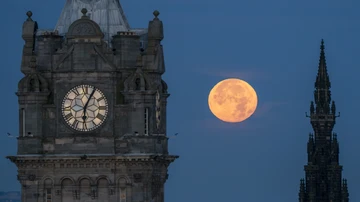 La superluna azul se pone entre el Reloj Balmoral y el Monumento a Scott en Edimburgo.