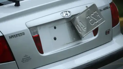 Imagen de un vehículo con la placa de matrícula parcialmente arrancada.
