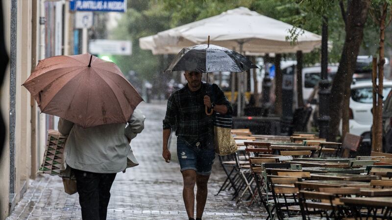 Varias personas se resguardan de la lluvia con paraguas en Madrid.