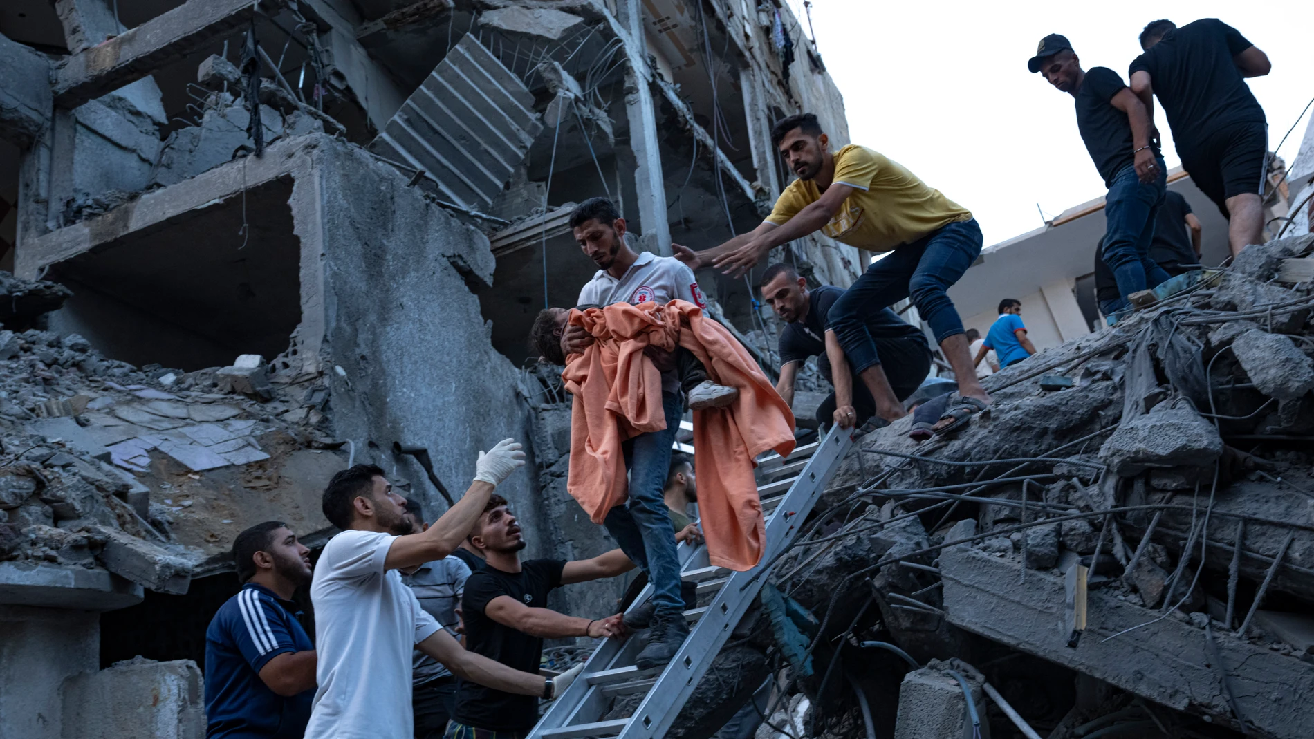 Ciudadanos palestinos rescatan a una niña entre los escombros de un edificio residencial destruido por fuerzas israelíes