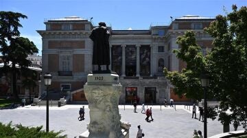 Goya observa a un grupo de personas desde lo alto de su pedestal delante del Museo del Prado