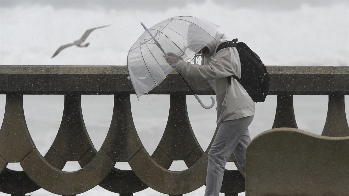 Una persona se protege de la lluvia y el viento con un paraguas en A Coruña. Una persona se protege de la lluvia y el viento con un paraguas en A Coruña.
