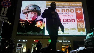 Un hombre pasa junto a una pantalla publicitaria que muestra a soldados del ejército ruso y promueve el servicio militar contratado en el ejército ruso en San Petersburgo, Rusia.