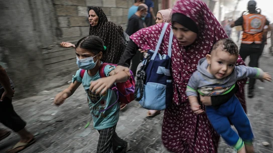 Mujeres y niños palestinos huyen tras un ataque aéreo israelí en la ciudad de Gaza. Mujeres y niños palestinos huyen tras un ataque aéreo israelí en la ciudad de Gaza.